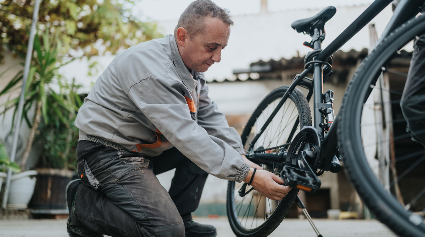 Mécanicien vélo présentant trois plateaux de tailles différentes sur un établi d'atelier